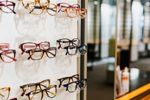 Brýlové obruby vystavené na stojanech v prodejně optiky