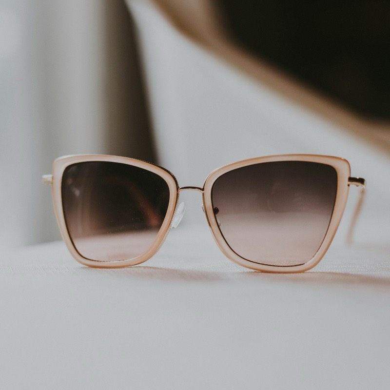 Sluneční brýle typu cat-eye s pudrovou obrubou na světlé látce